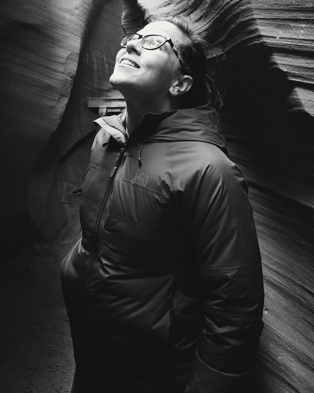 Annie Memmott standing in a slot canyon, looking up toward the light.
